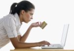 Teenage girl holding a credit card working on a laptop