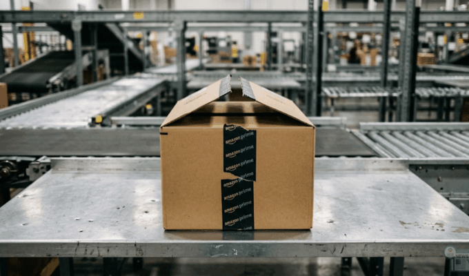 Pacco Amazon parzialmente aperto su un banco da lavoro metallico in un centro logistico.