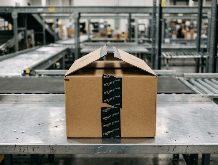 Pacco Amazon parzialmente aperto su un banco da lavoro metallico in un centro logistico.