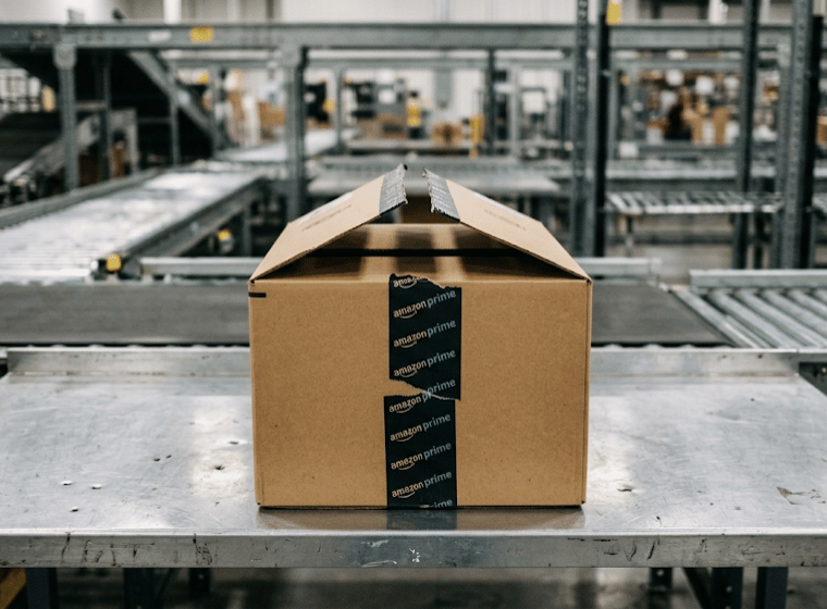 Pacco Amazon parzialmente aperto su un banco da lavoro metallico in un centro logistico.